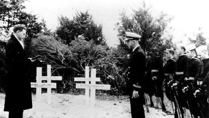 Black and white image of sailors commemorating gravestones in Ocracoke.