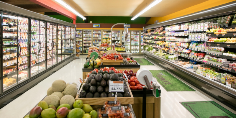 Frozen aisle at grocery store with carts of fruits and vegetables.