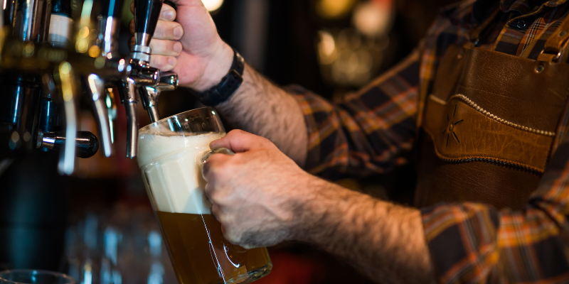 Person pouring beer into mug from tap.